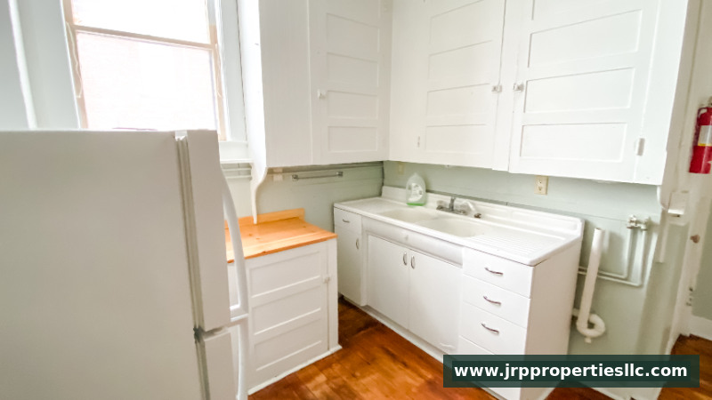 Bright kitchen with refrigerator, sink, and white cabinetry